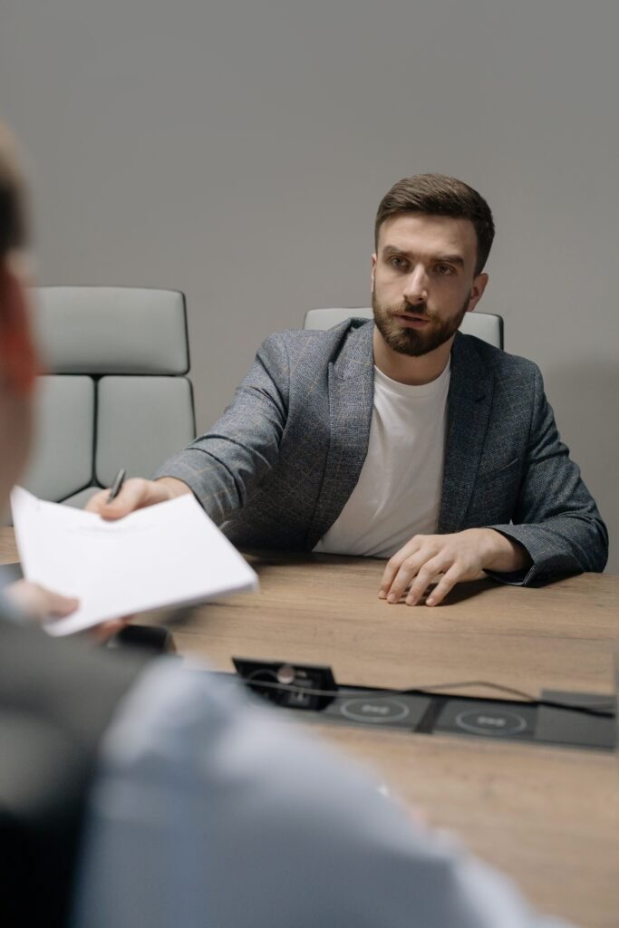 pexels-photo-6814534-6814534 A man in a blazer negotiating across a table in a modern office setting.